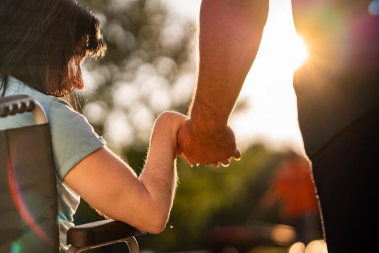 Man holding wife's hand in wheelchair, symbolizing support after a car accident and legal assistance.