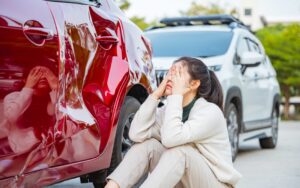 Woman inspecting vehicle damage after an Oklahoma car accident