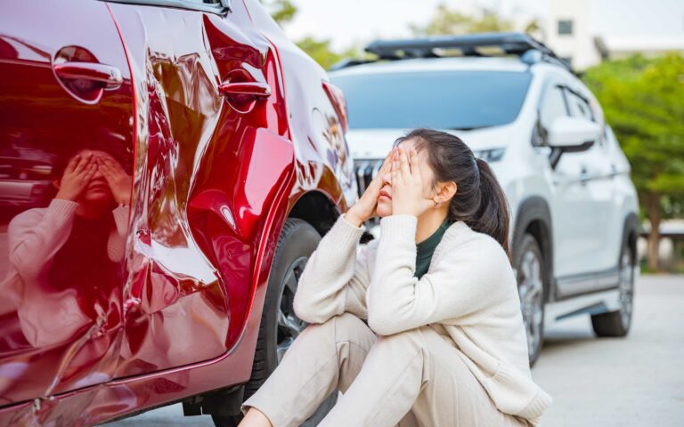 Woman inspecting vehicle damage after an Oklahoma car accident